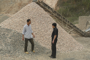 Anh Tòng Văn Thanh (người bên trái) giới thiệu với cán bộ NHCSXH Kim Bôi về dàn máy nghiền đá được đầu tư bởi vốn vay ưu đãi.